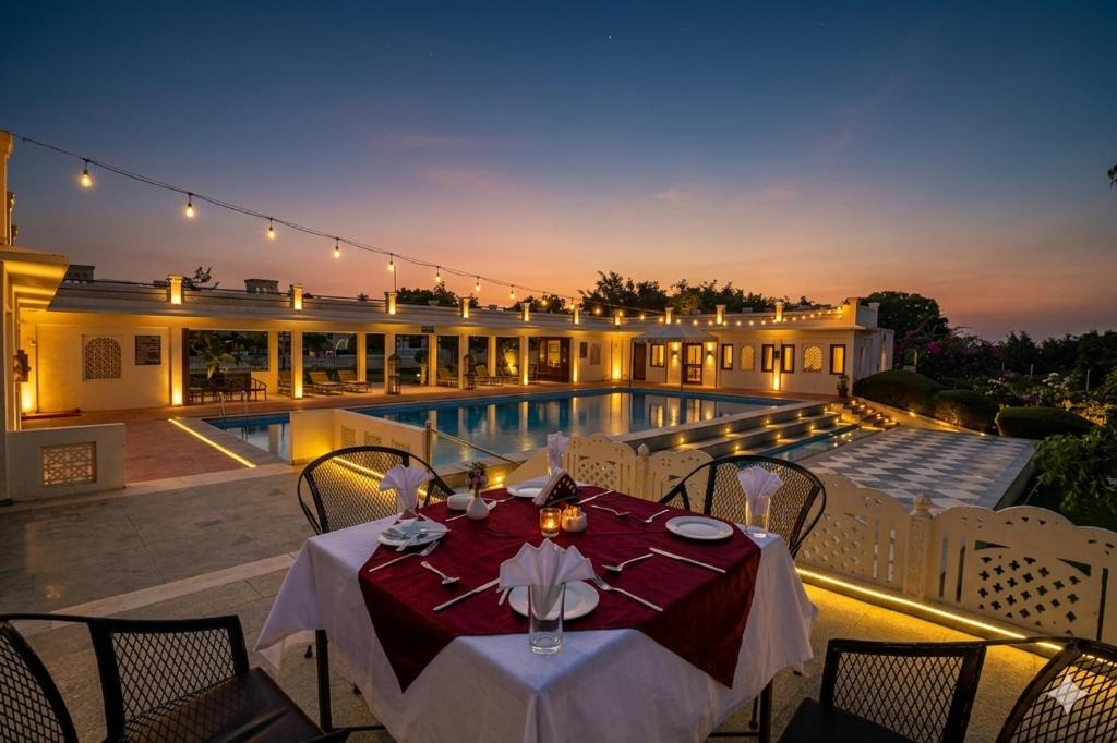 a dining table on a patio next to a pool at Aaram Baagh Pushkar by Pachar Group in Pushkar