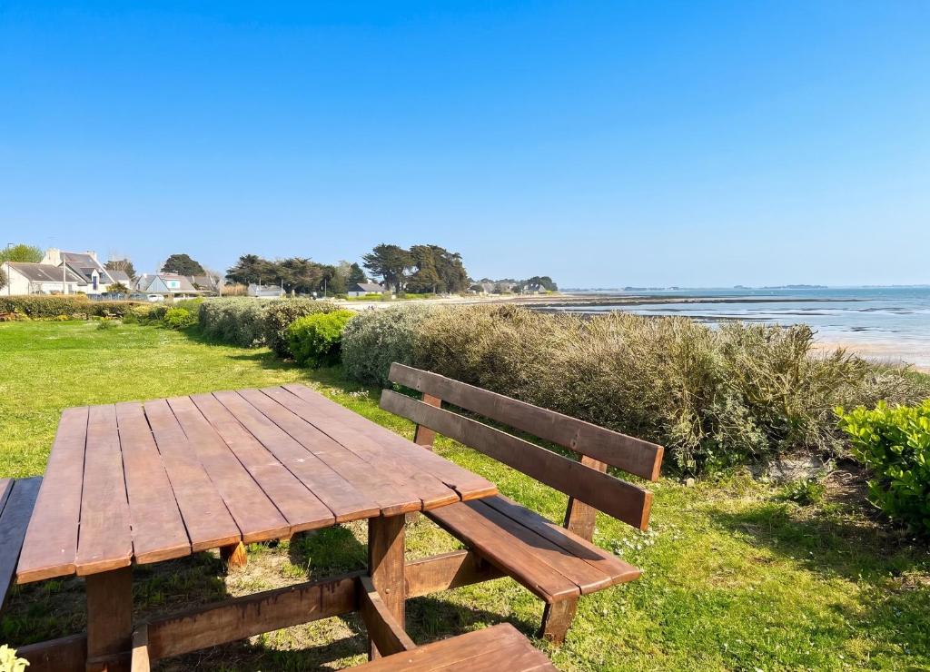 a wooden picnic table sitting next to the beach at Appartement charmant à Sarzeau avec vue sur la mer, 55 m² in Sarzeau