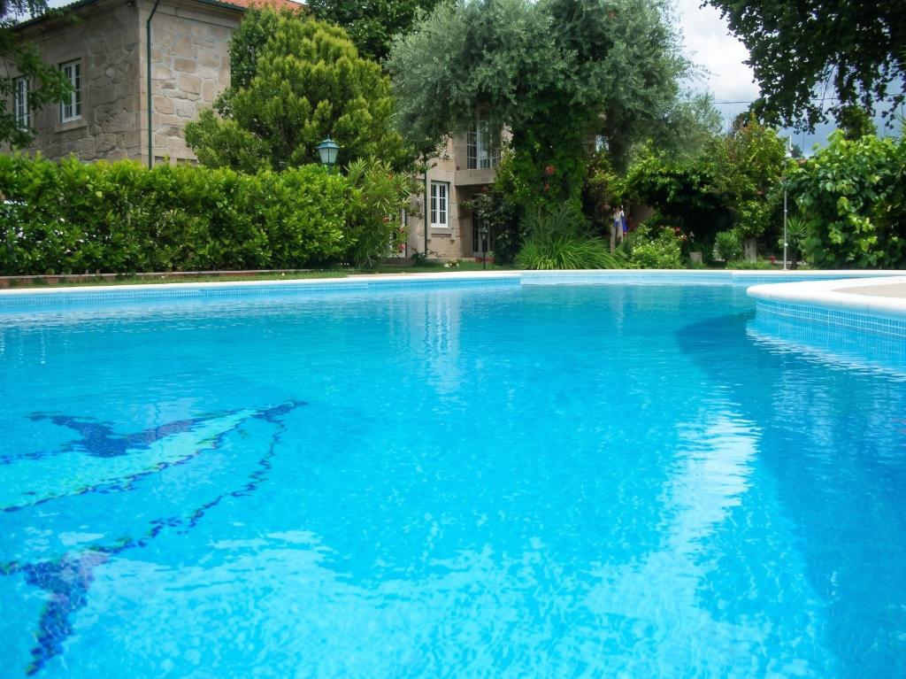 a swimming pool with blue water in front of a building at Charming villa with mountain view in Pedraça, pool in Pedraça