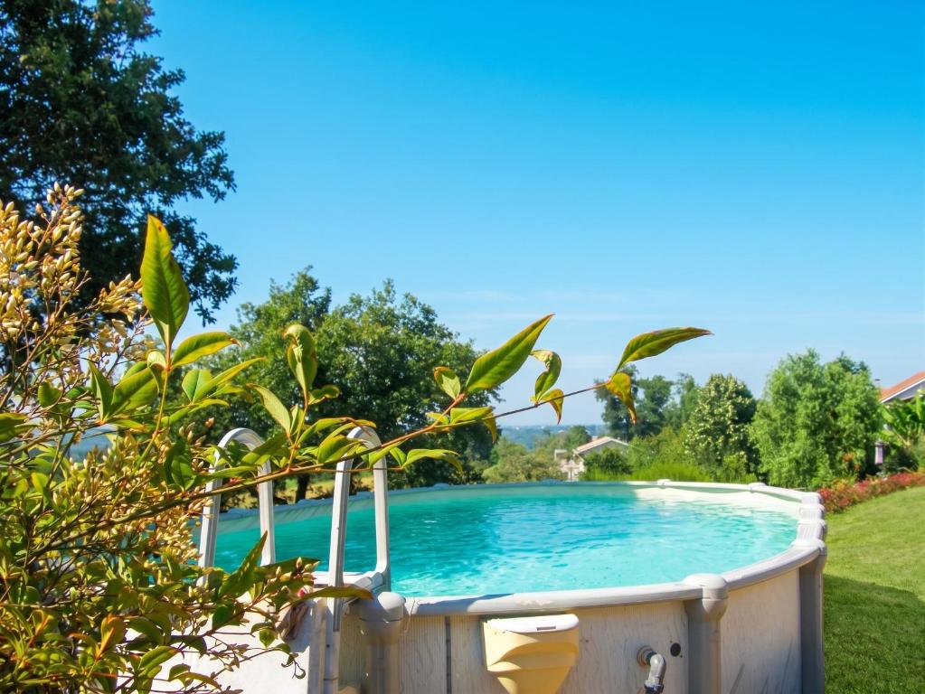 a swimming pool in a yard with trees at Maison cosy avec piscine privée à Estibeaux 38 m² in Estibeaux
