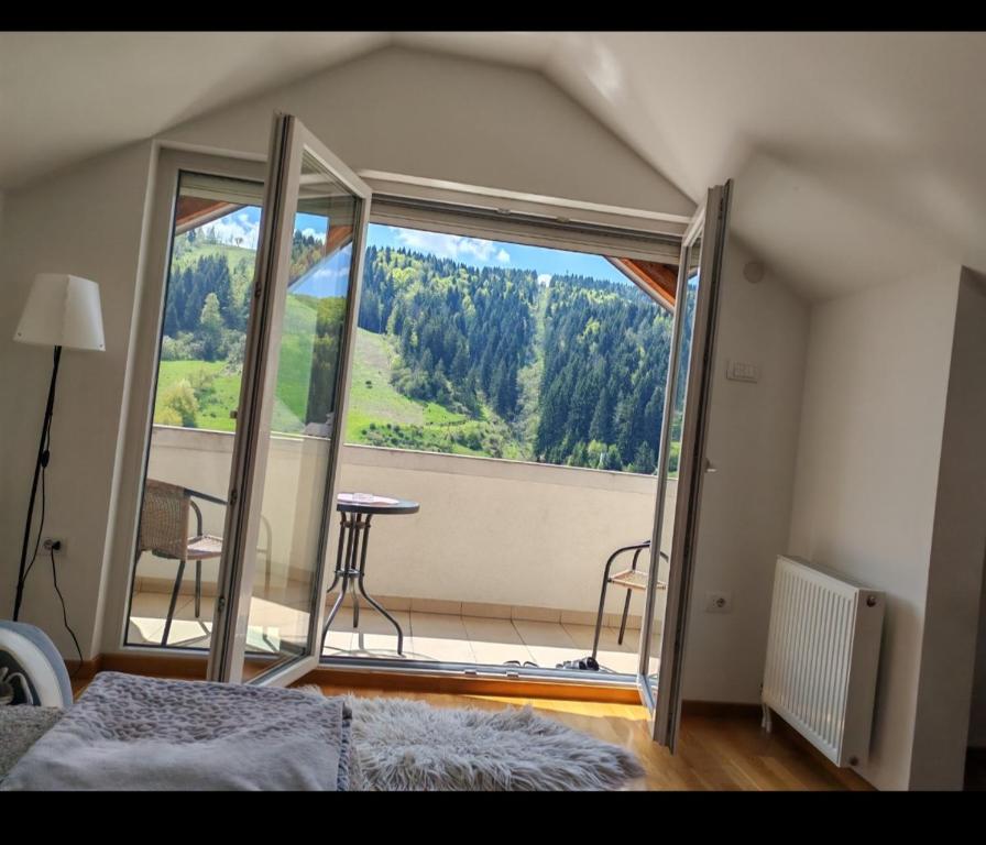 a bedroom with a large window with a table and chairs at Duh Zlatara in Nova Varoš