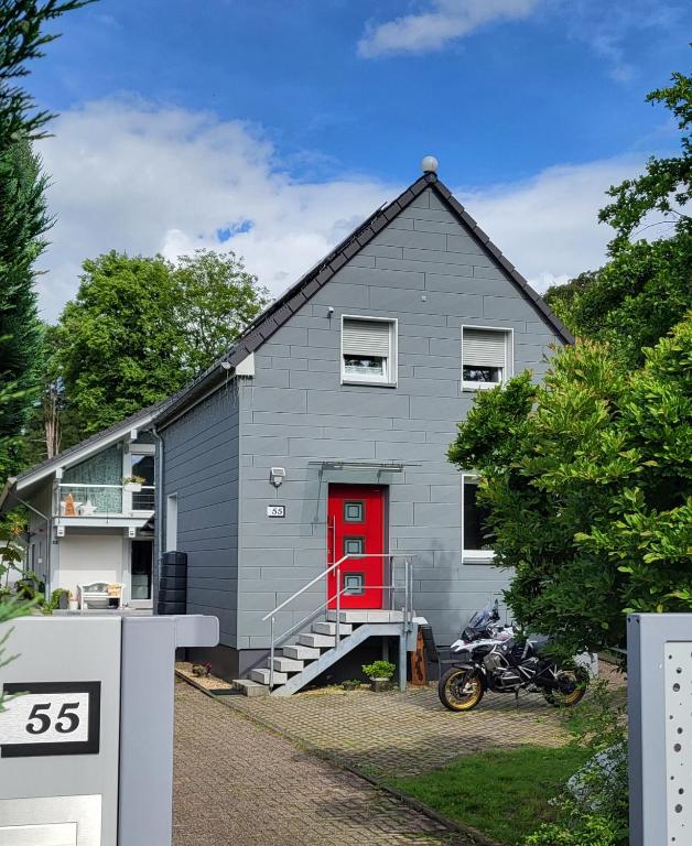a gray house with a red door and a motorcycle at Leichlingen 1 in Leichlingen