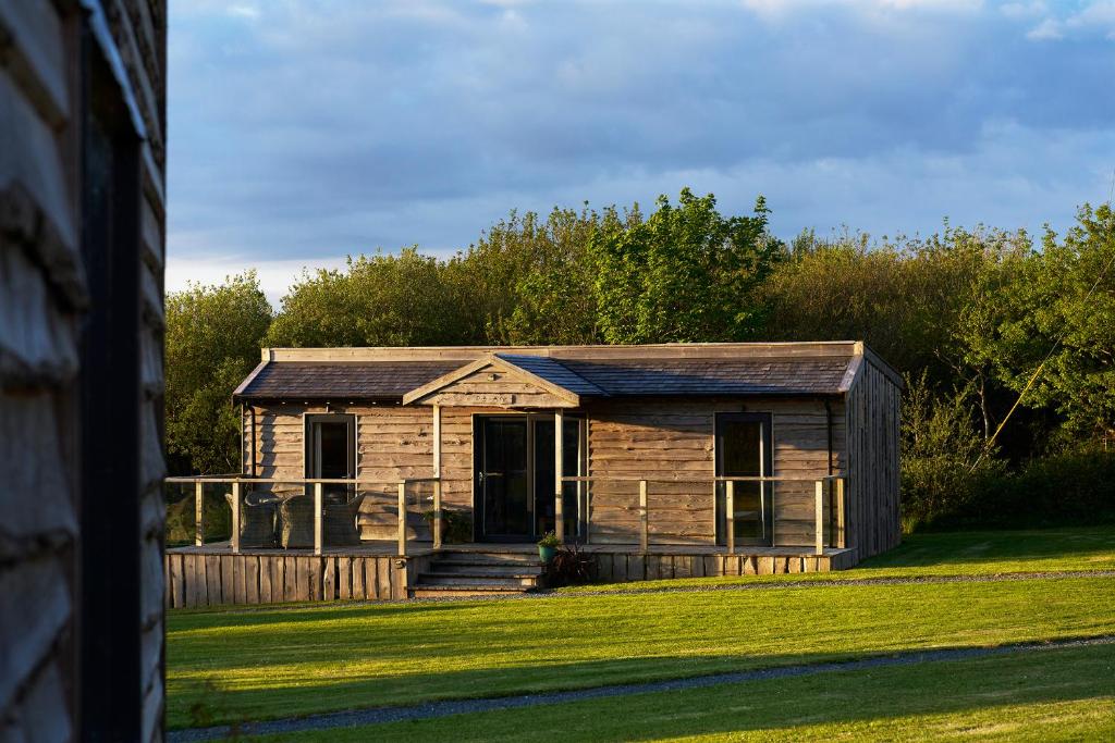 an old log cabin on a grass field at The Piggery at Little Pig in Bude