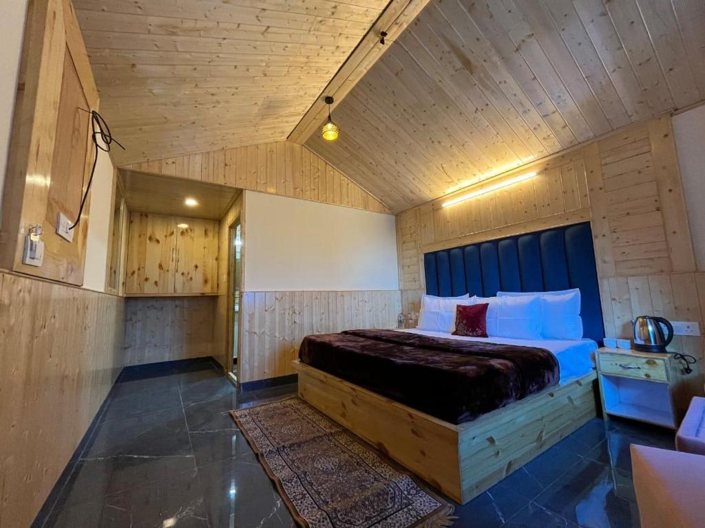 a bedroom with a large bed with a wooden ceiling at AP cottage and huts in Manāli