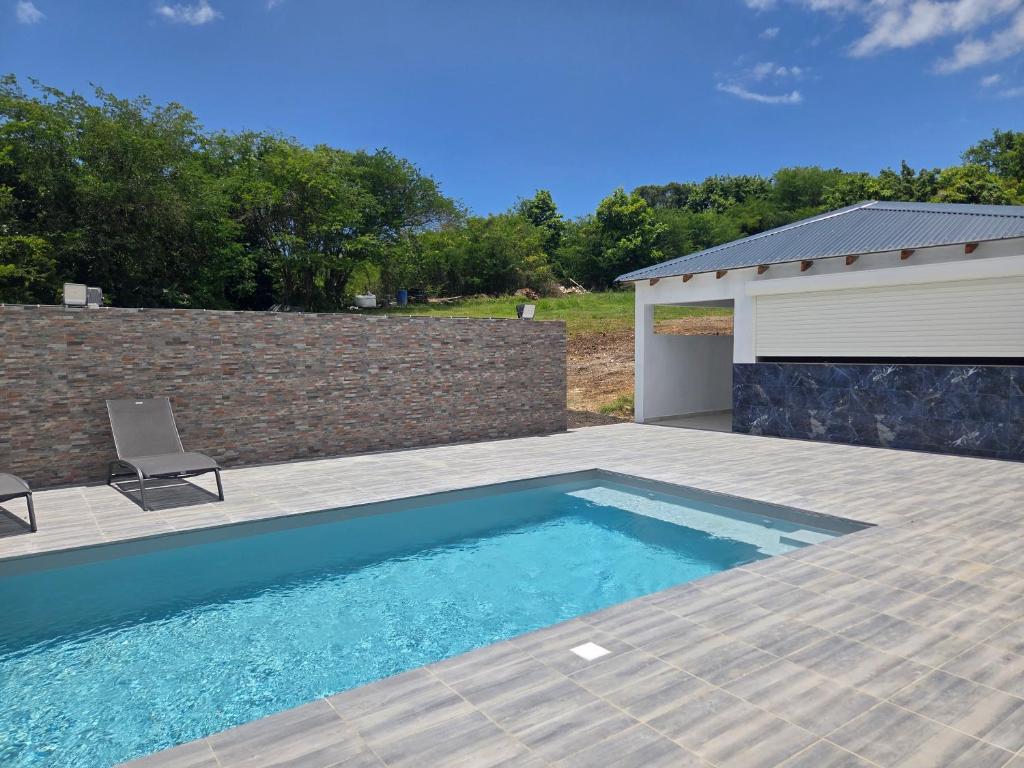 a swimming pool with a patio and a building at VILLA Orchidée in Le Moule