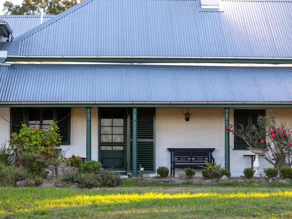 a house with a blue roof and a bench at Lochinvar House in Lochinvar