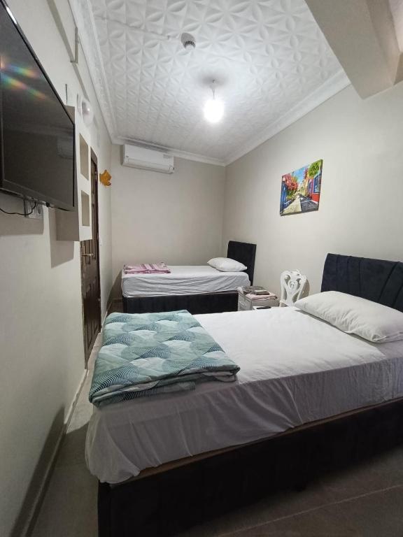 a room with two beds and a flat screen tv at Girasun otel in Jesıret ibn Omar