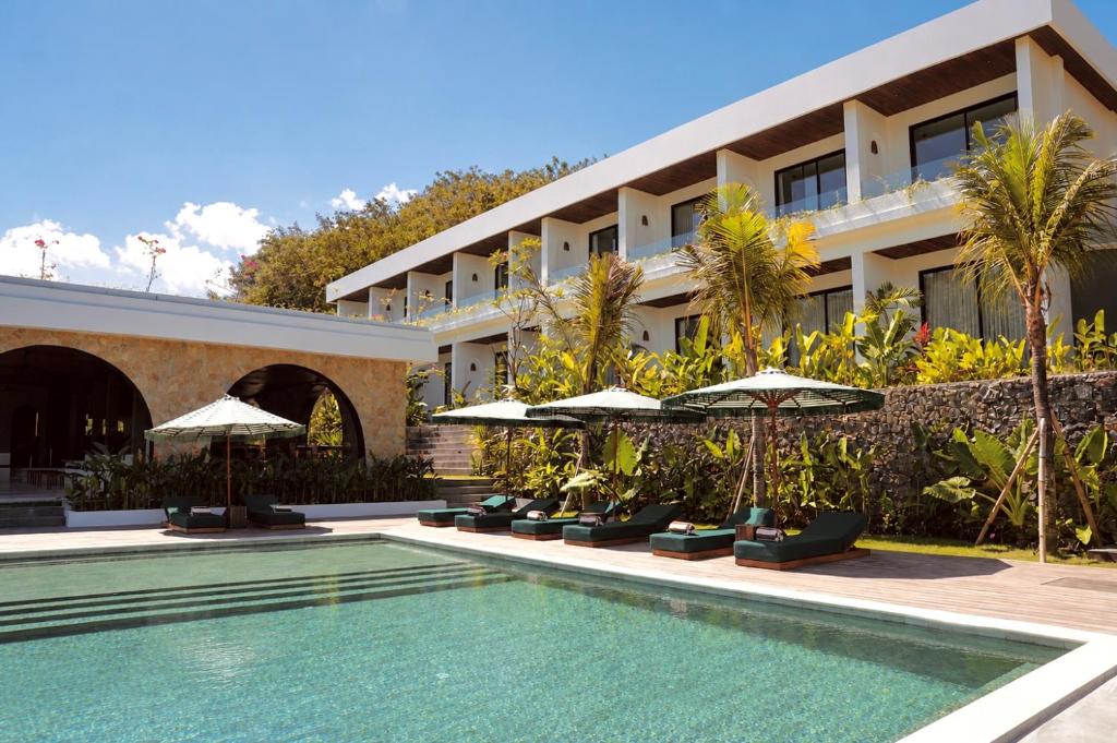 a resort with a swimming pool and umbrellas at Kanalla Boutique Hotel - Adults Only in Kuta Lombok