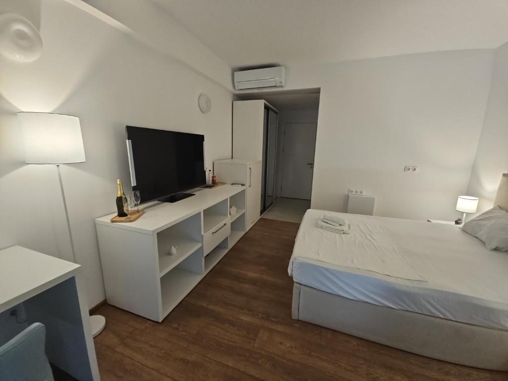 a white bedroom with a bed and a flat screen tv at Blue Sea OLIMP by Any - Etaj PREMIUM cu vedere la Mare in Olimp