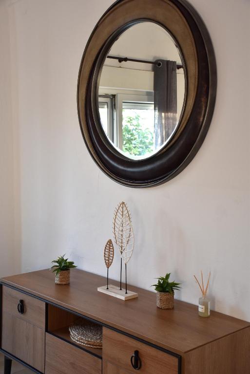 a mirror on a wall above a wooden dresser at Sxoleio Apartment in Kamariotissa