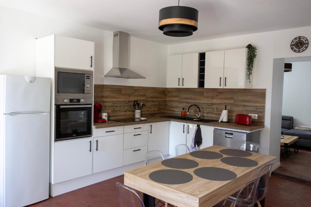 a kitchen with white cabinets and a wooden table at Gîte de la Dheune in Essertenne