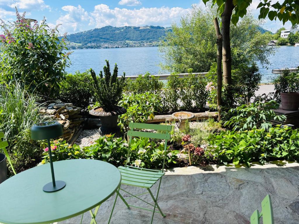 a table and chairs in a garden with a view of the water at See Apartment Traunsteinstrasse in Gmunden