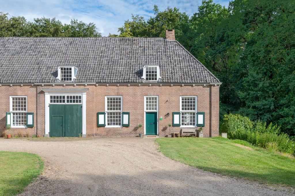 a brick house with green doors and a gravel driveway at Zwaluwenburg 4 in 't Harde