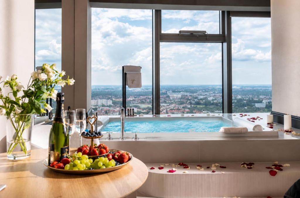 a bathroom with a tub with a bowl of fruit on a table at Apartamenty Sky Tower in Wrocław