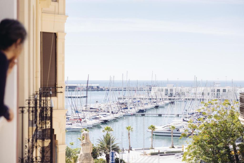 a woman looking out a window at a marina with boats at Casa Alberola Apartments in Alicante