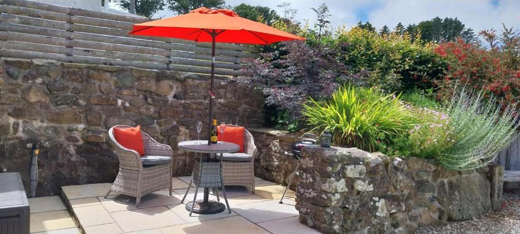 a table and chairs with an umbrella in a garden at 1 Bed in Sarn oc-y29230 in Bottwnog