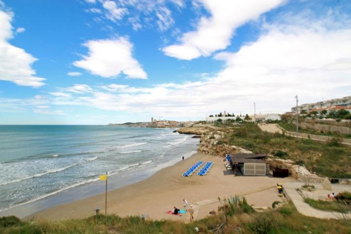 einen Strand mit blauen Liegestühlen und dem Meer in der Unterkunft Casa Cala Balmins in Sitges