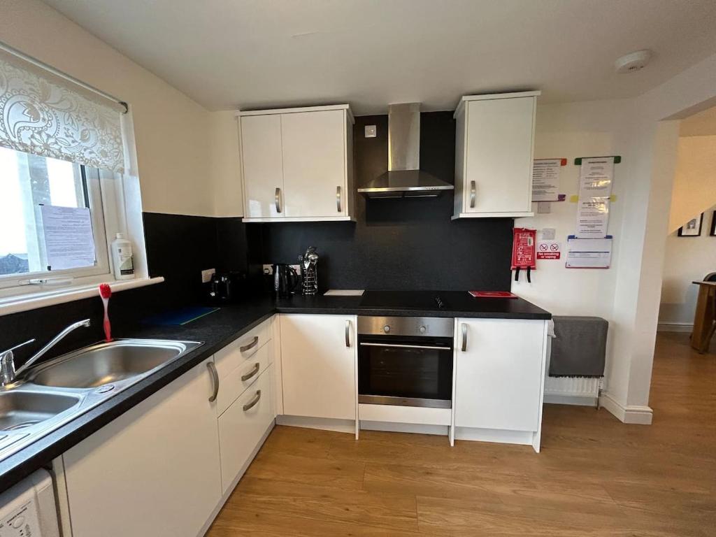a kitchen with white cabinets and a sink at Carley's House - Macduff Seaside Escape in Macduff