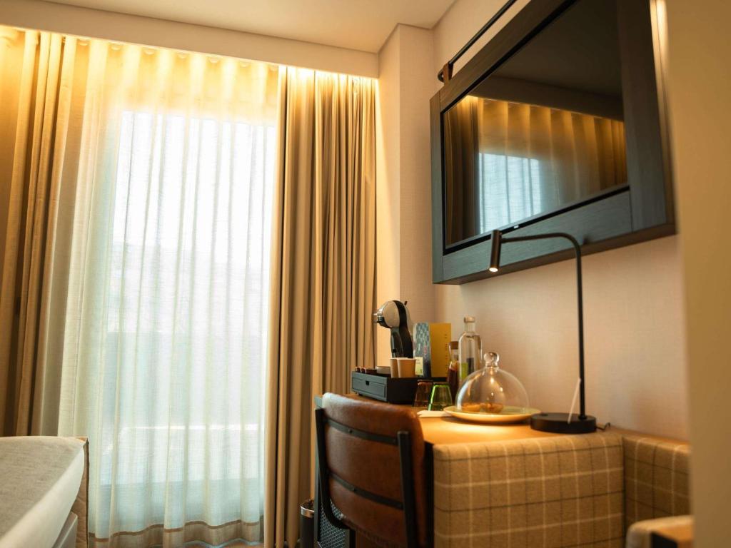 A compact desk and beverage station beside a bright curtained window.