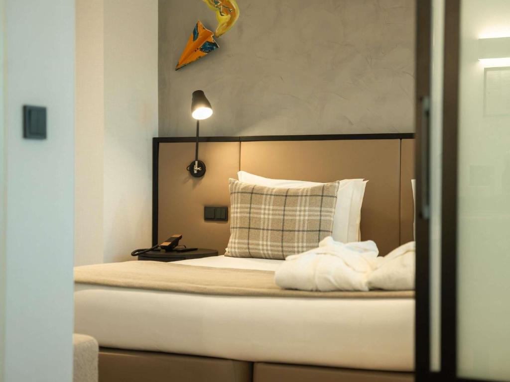 A bed viewed through the doorway, with a padded headboard, bedside lamp and compact bedside table.