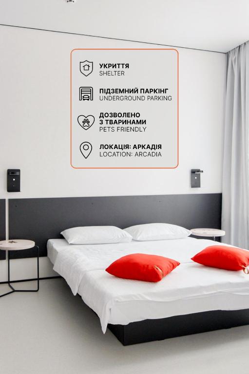 a bed with two red pillows and a sign above it at Atmosfera Hotel in Odesa