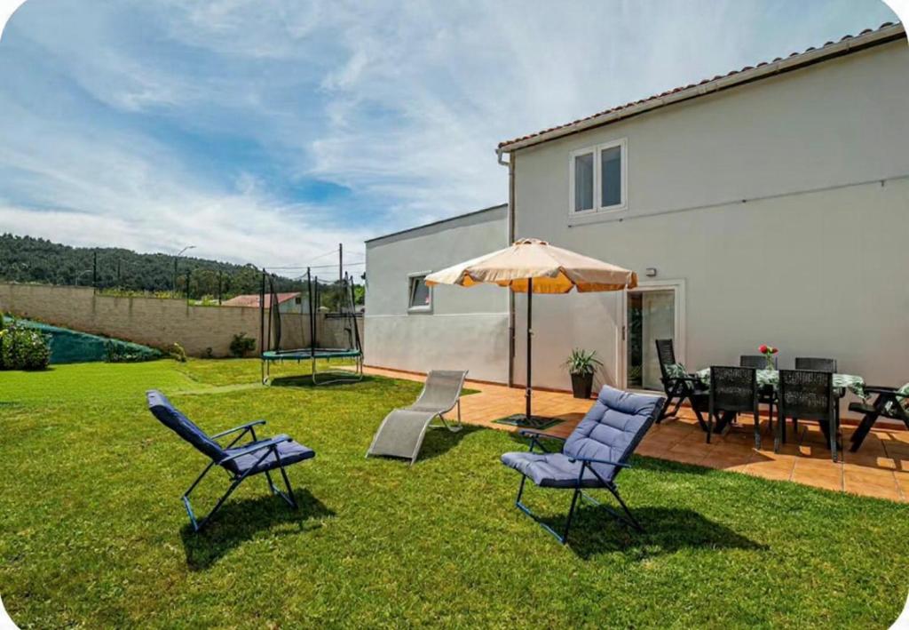 a yard with chairs and an umbrella and a table at Alola in Lousame