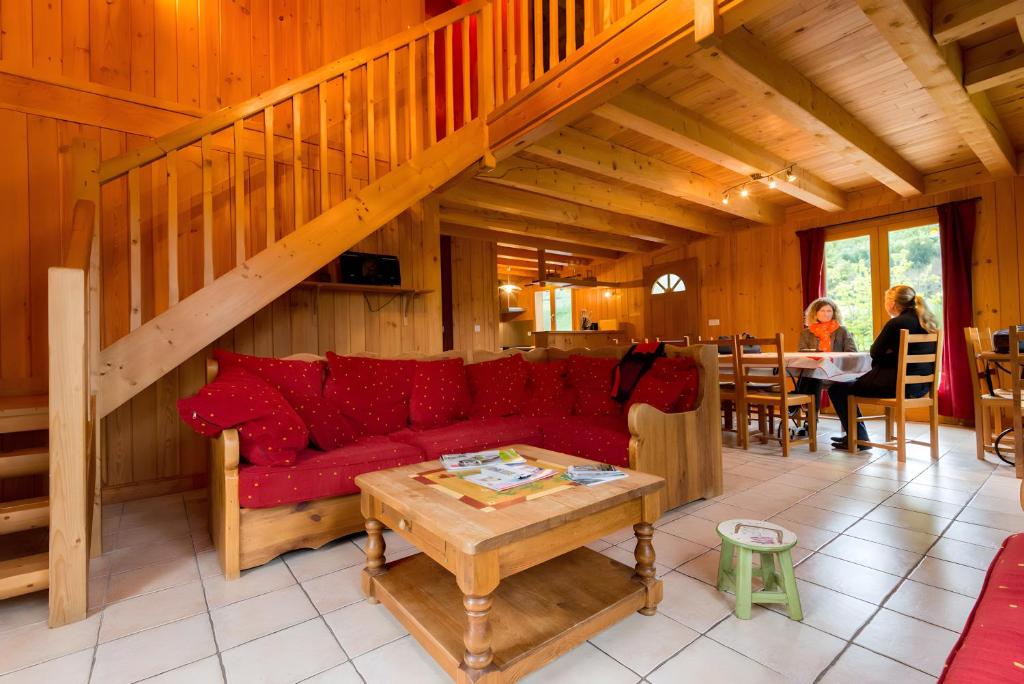 a living room with a red couch and a table at Chalet Bien-être, Piscine, Spa in La Chapelle-dʼAlagnon