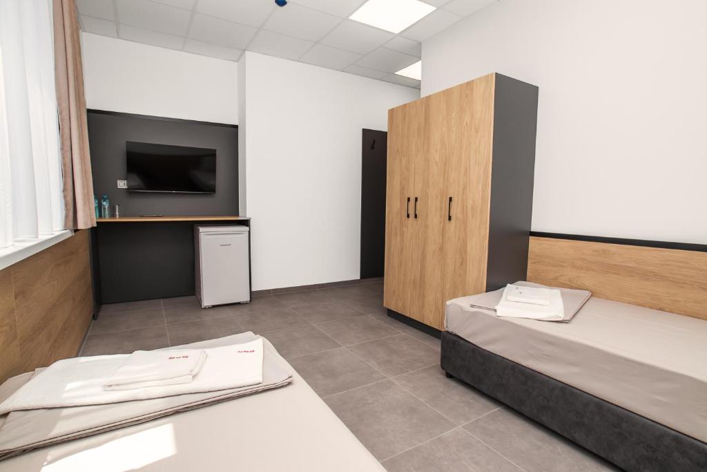 a room with two beds and a tv on a wall at Хотел КО НИ КО in Stara Zagora