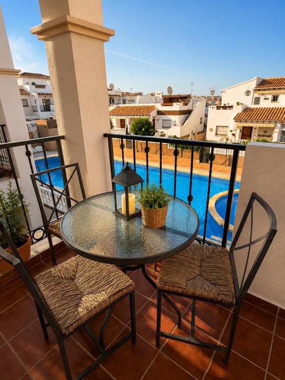 a glass table and chairs on a balcony with a pool at Almohabenos Pool View in Punta Prima