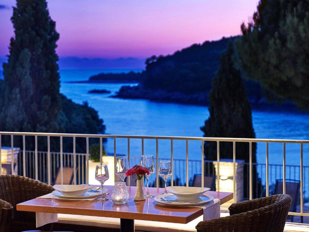 a table on a balcony with a view of the ocean at Movenpick Resort Agios Nikolaos Sivota in Syvota