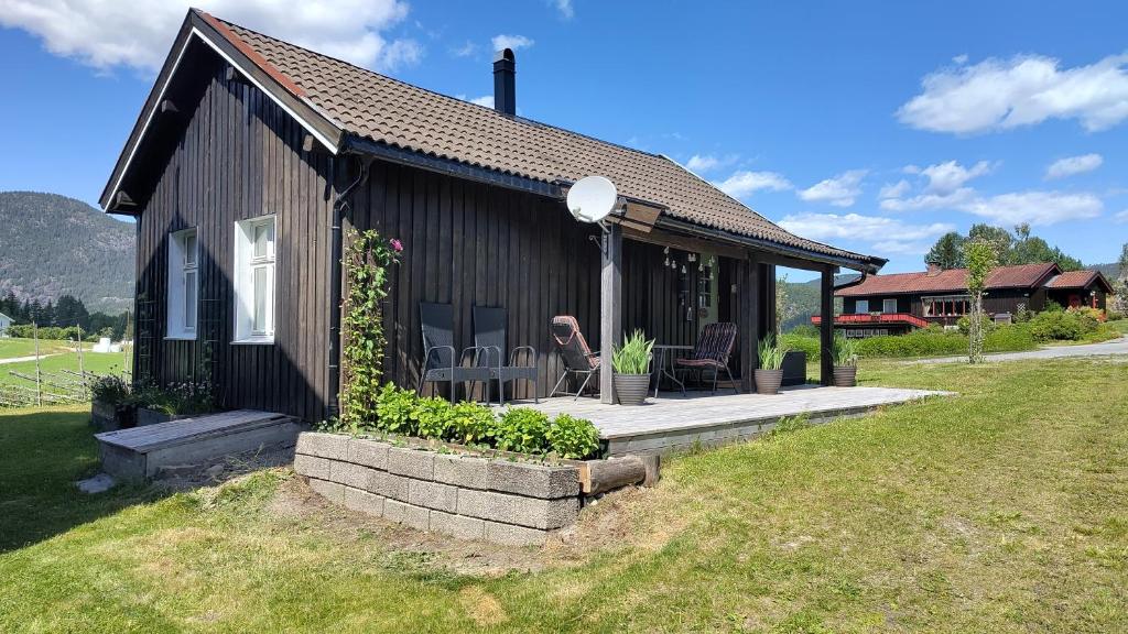 a small black house with a porch and two chairs at Suigard Veslestugo in Sauland