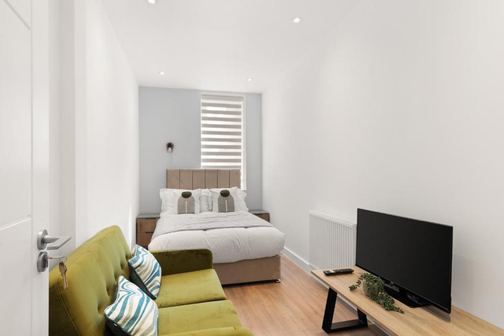 a living room with a bed and a television at Bright 2BR Flat Close to Shops in Beckenham in Beckenham