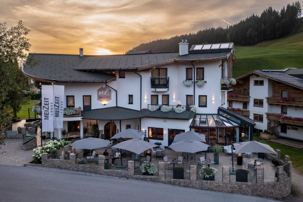 a hotel with tables and umbrellas in front of it at meiZeit Lodge in Filzmoos