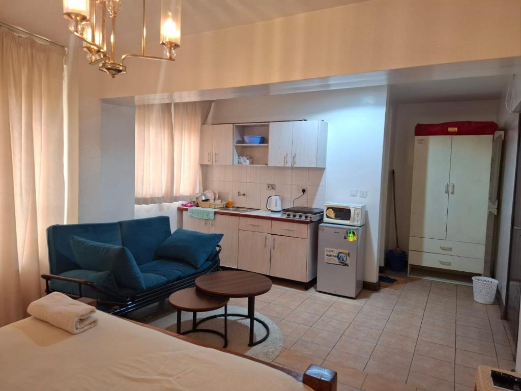 a living room with a blue couch and a kitchen at Executive Express Rooftop Pool suites- Ngara in Nairobi
