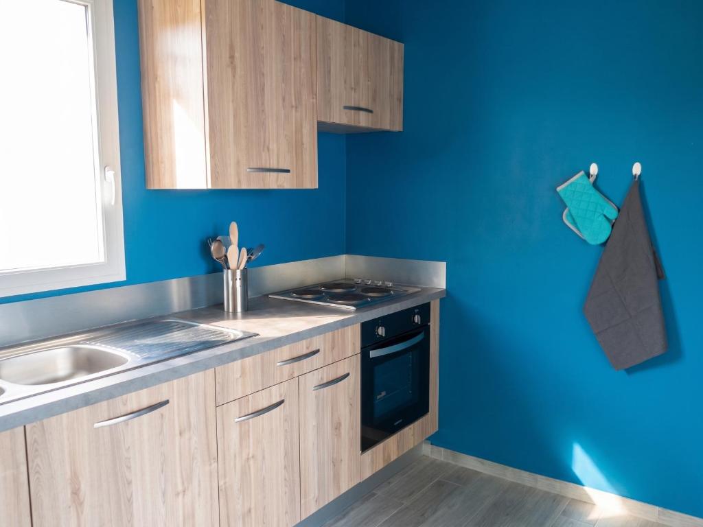 a blue kitchen with a sink and a stove at Villa charmante au Moule avec piscine in Le Moule