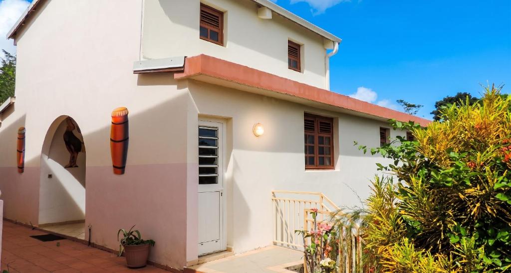 a white house with a door and a fence at Appartement confortable au Robert 70 m² avec jardin privé in Le Robert