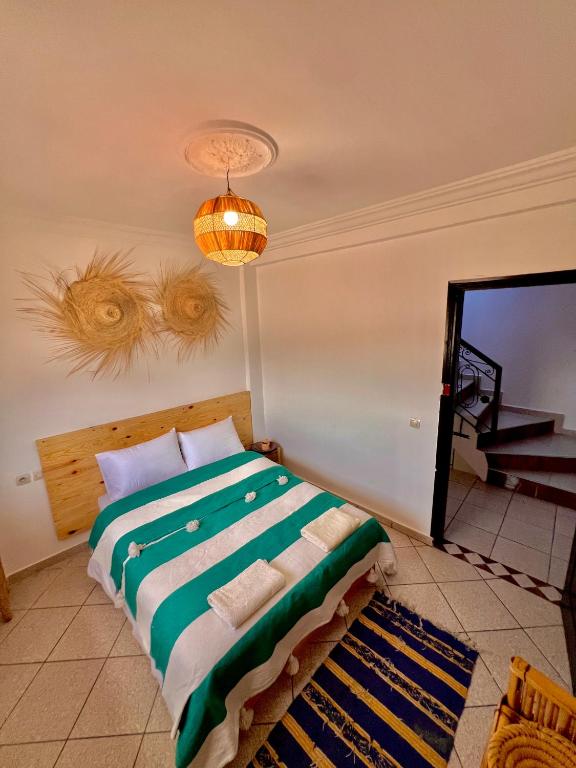 a bedroom with a bed and a chandelier at Amzil Surf House in Aourir
