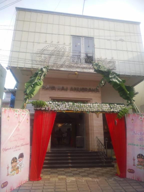 an entrance to a building with red curtains and flowers at Raya Raj Anugraha in Kumbakonam