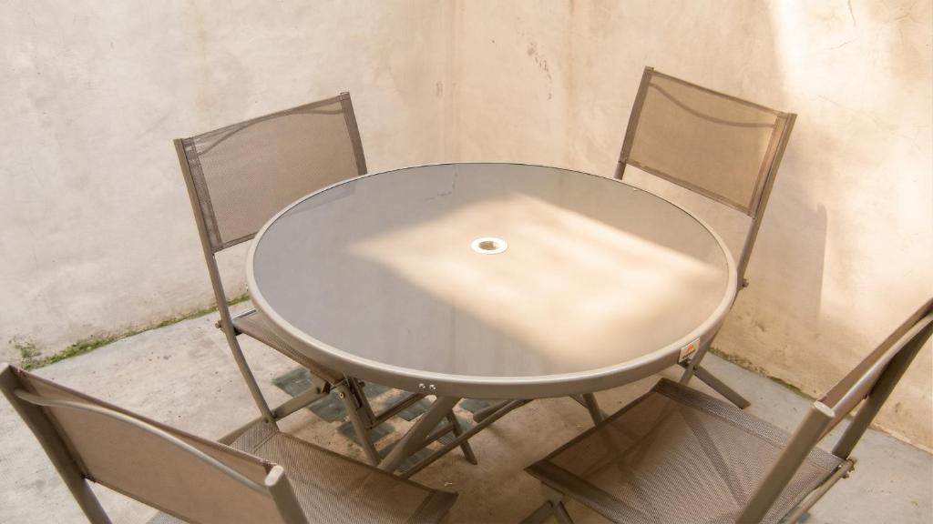 a glass table with three chairs around it at Maison charmante à Montblanc avec terrasse in Montblanc