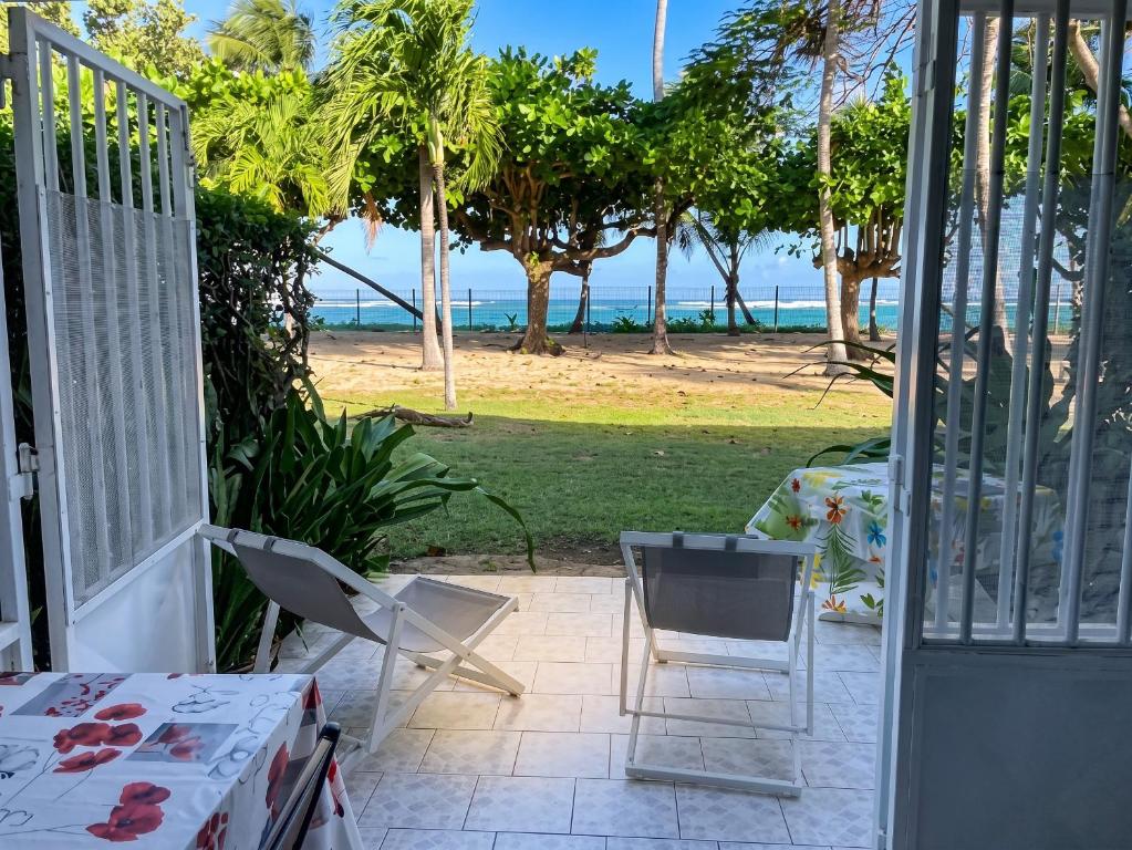 an open door to a patio with a view of the beach at Charmant studio avec vue sur mer au Moule, 20 m² + terrasse in Le Moule