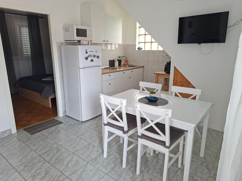 a kitchen with a table and chairs and a white refrigerator at Apartman Meli in Rab