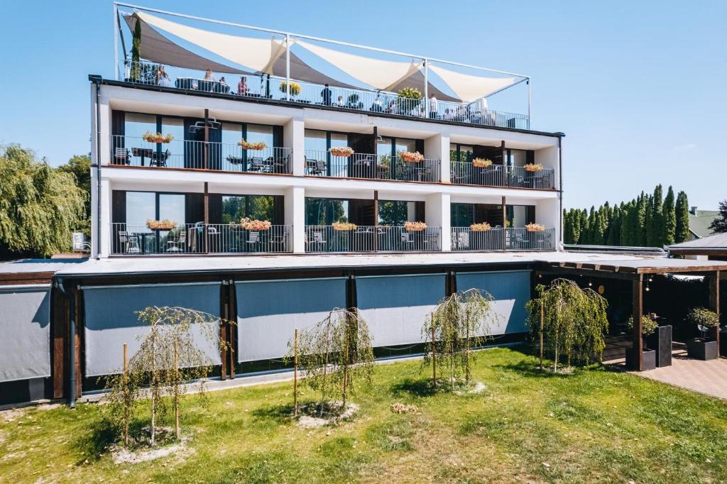 a large white building with plants in front of it at Port étterem&panzió in Balatonmáriafürdő