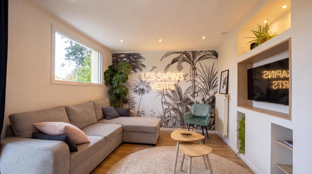 a living room with a couch and a tv at Les sapins verts - vue haras in Saint Lo