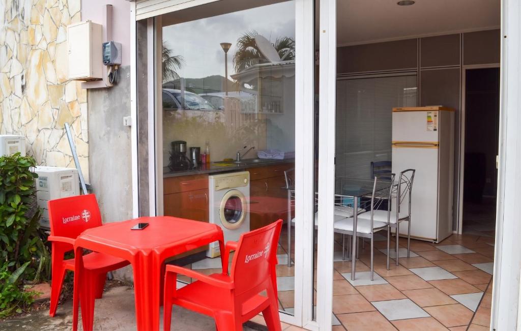 a kitchen with a red table and chairs and a kitchen with a washing machine at Appartement confort au Diamant 25 m² terrasse in Le Diamant