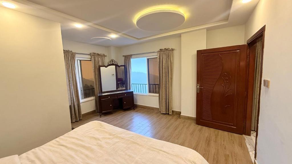 a bedroom with a bed and a mirror and windows at Shareef Lodge in Murree