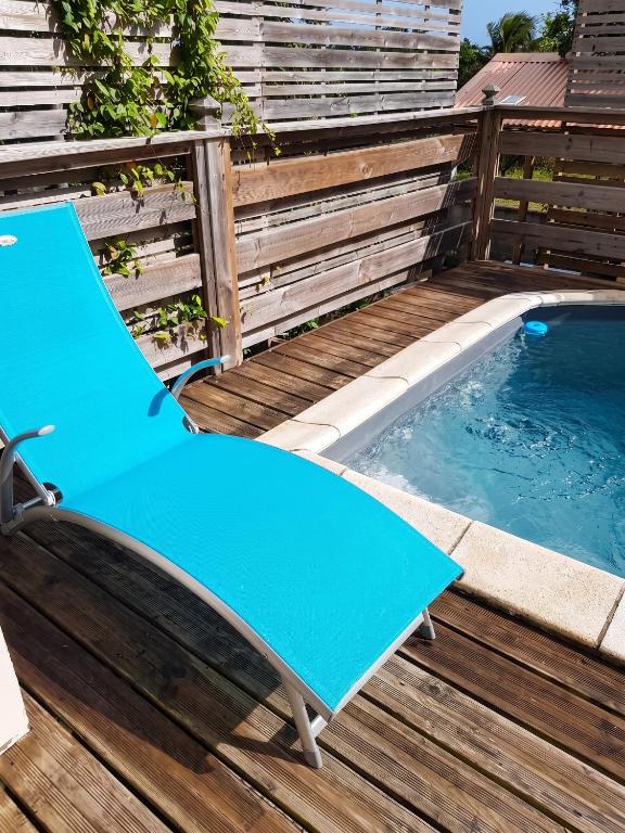 a blue chair sitting on a deck next to a swimming pool at Maison confortable Le Moule Jacuzzi in Le Moule
