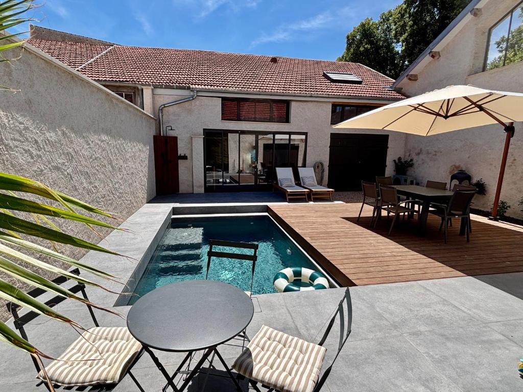 a pool with a table and chairs and an umbrella at Appartement avec jacuzzi et piscine sur les remparts in Langres