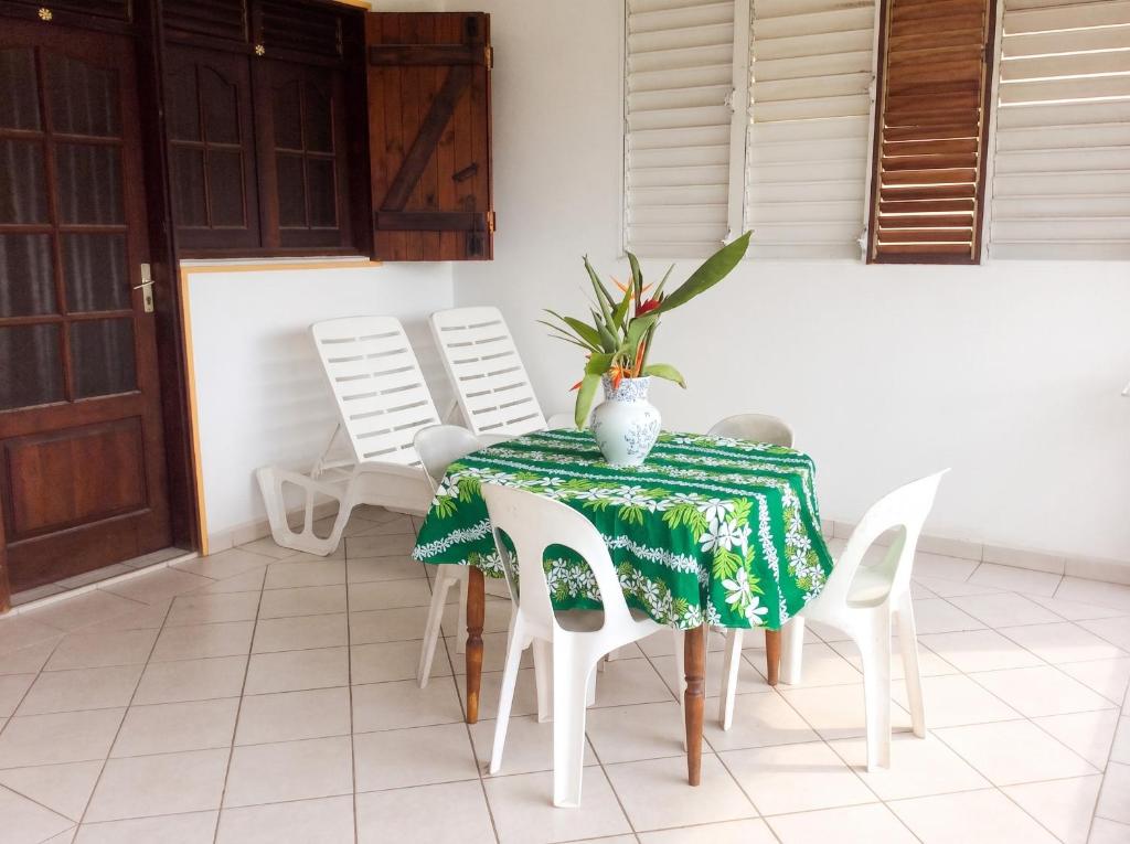a table with chairs and a vase on top of it at Appartement spacieux à Petit Canal - 65 m² - Vue sur jardin in Petit-Canal