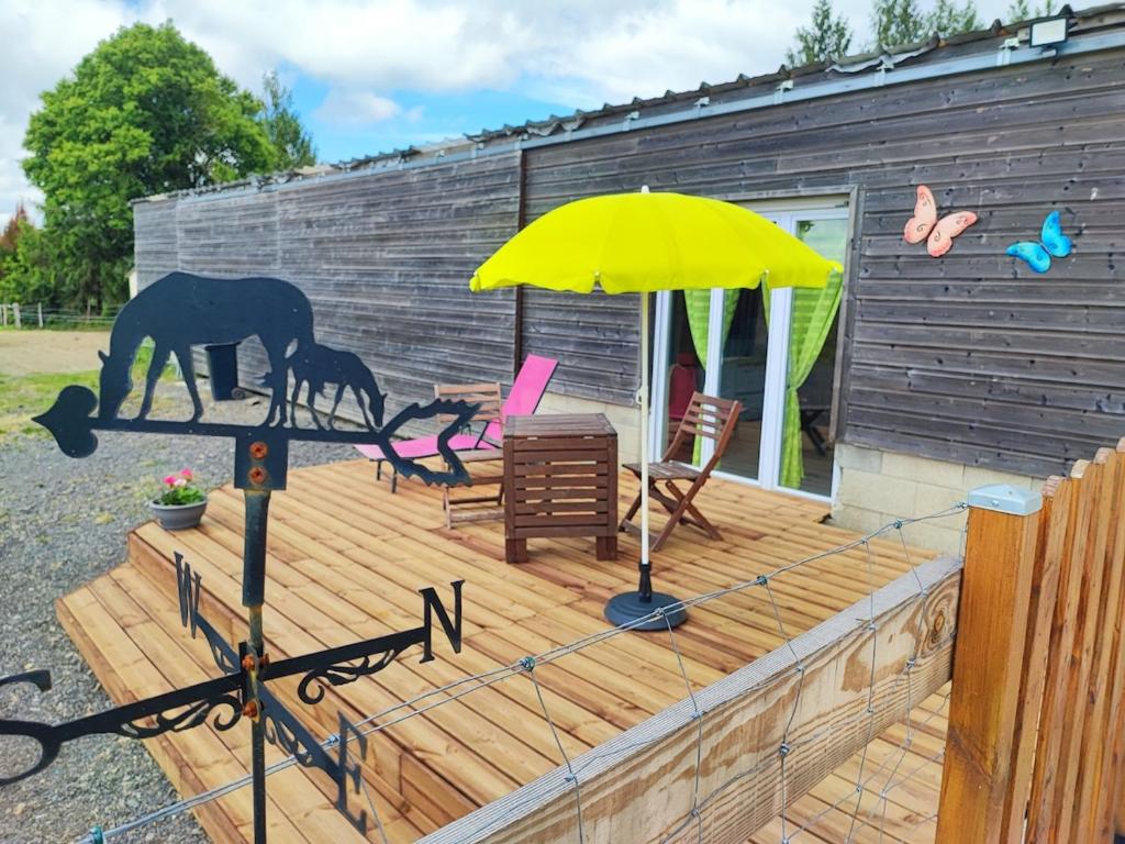 a wooden deck with a horse and a yellow umbrella at Studio des Mèzerets in La Chapelle-Engerbold