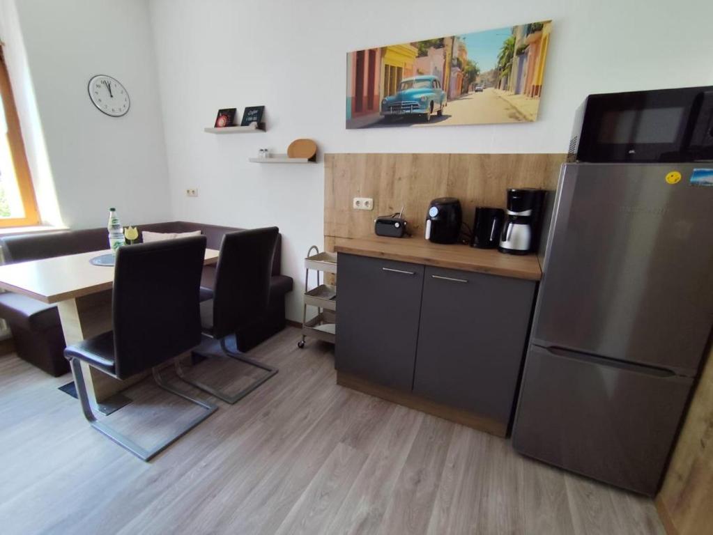 a kitchen with a refrigerator and a table with chairs at NEU! Fereinwohnung Greim in Lengenfeld